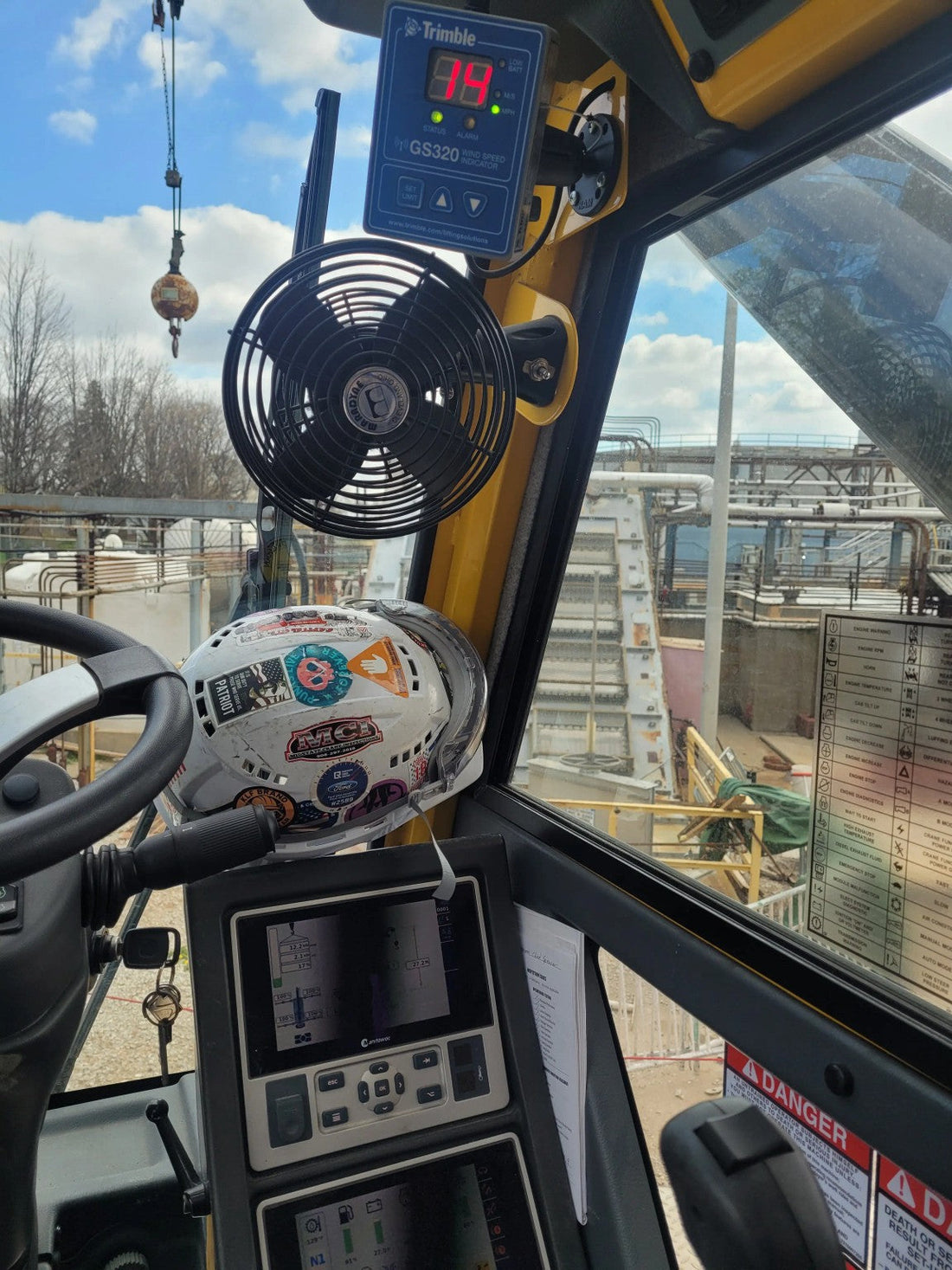 Crane operator cab inside a GRT655 at a refinery with hardhat and controls visible during standby